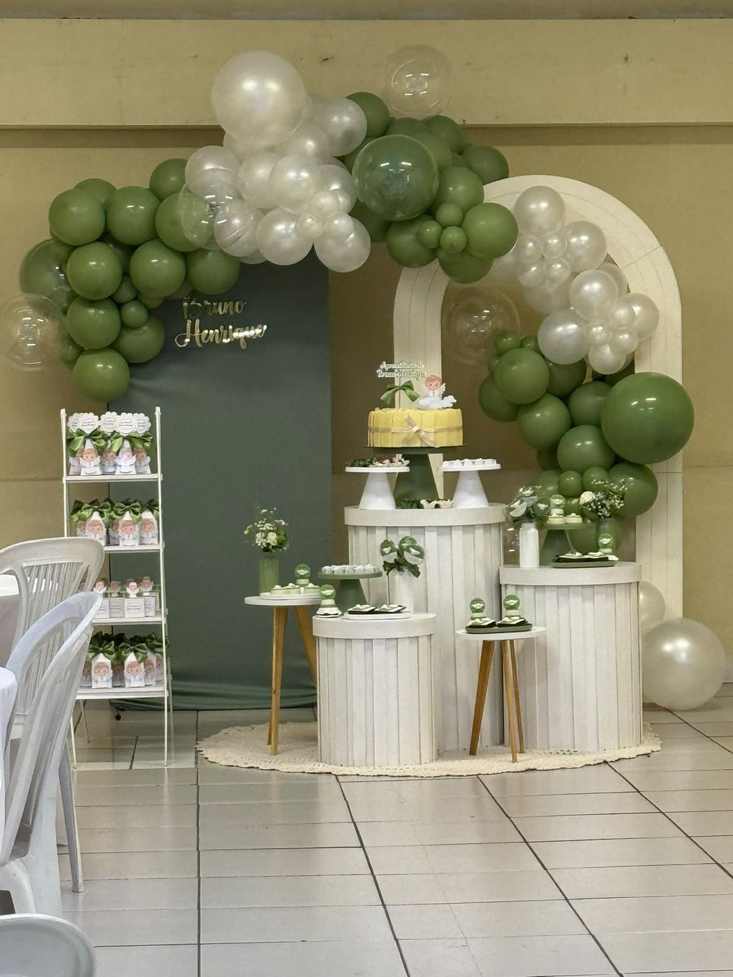 Batizado em verde sage e branco com arco de balões e anjinho