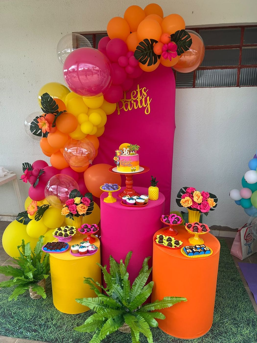 Decoração tropical Let's Party em rosa, laranja e amarelo com folhagens